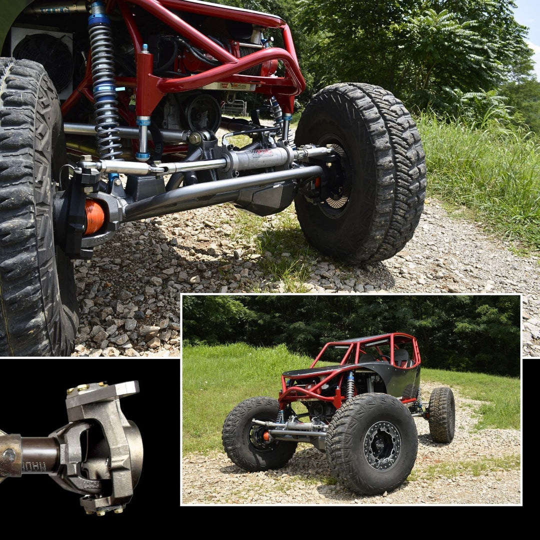 Off-road vehicle chassis with heavy duty Dana 60 kingpin knuckles and large tires on a gravel path, surrounded by greenery.