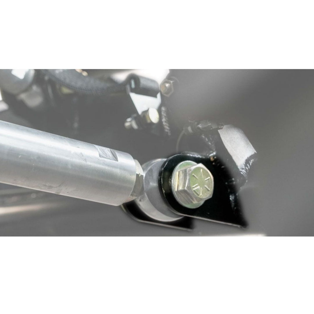 Close-up of a laser cut steel link tab and suspension bracket on a vehicle.