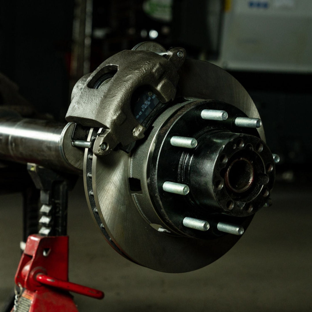 Close-up of a 3/4 ton disc brake upgrade kit for 14 bolt axle on an axle in a garage