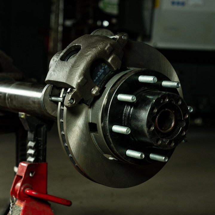 Close-up of a 3/4 ton disc brake upgrade kit for 14 bolt axle on an axle in a garage